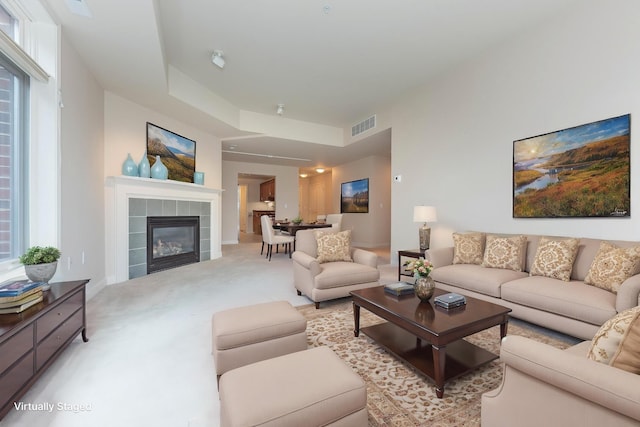 living area featuring light colored carpet, visible vents, a fireplace, and baseboards