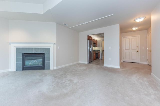 unfurnished living room featuring baseboards, light carpet, a tiled fireplace, and visible vents