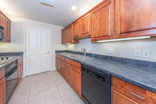 kitchen with a sink, dark stone counters, brown cabinetry, black appliances, and light tile patterned flooring
