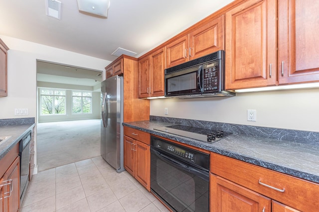 kitchen with brown cabinets, visible vents, black appliances, light carpet, and light tile patterned flooring