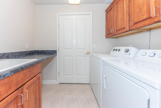 clothes washing area with washing machine and dryer, light tile patterned floors, baseboards, a sink, and cabinet space