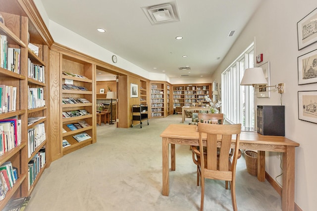 office featuring carpet, wall of books, visible vents, built in features, and recessed lighting