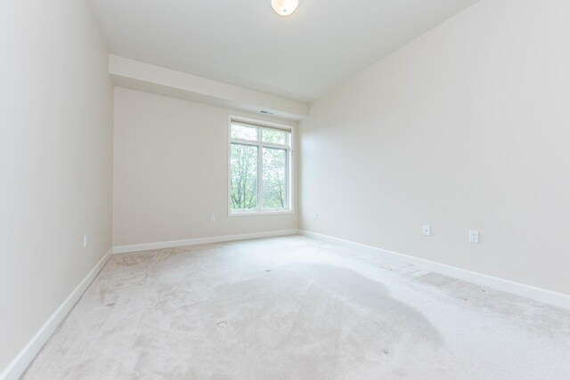 empty room featuring light carpet and baseboards