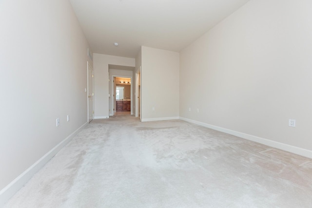 spare room with light carpet and baseboards