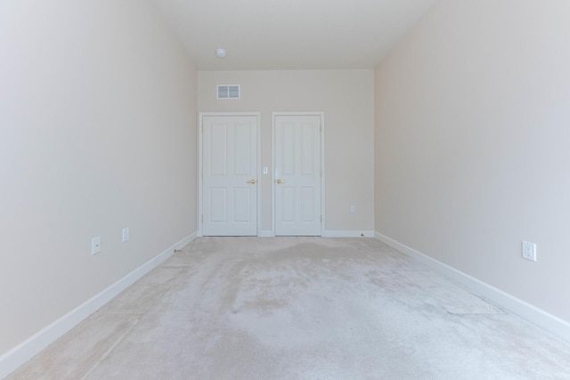 unfurnished bedroom featuring baseboards, visible vents, and light colored carpet