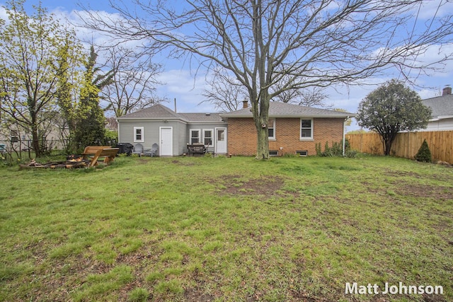 back of property featuring a yard, brick siding, a chimney, and fence
