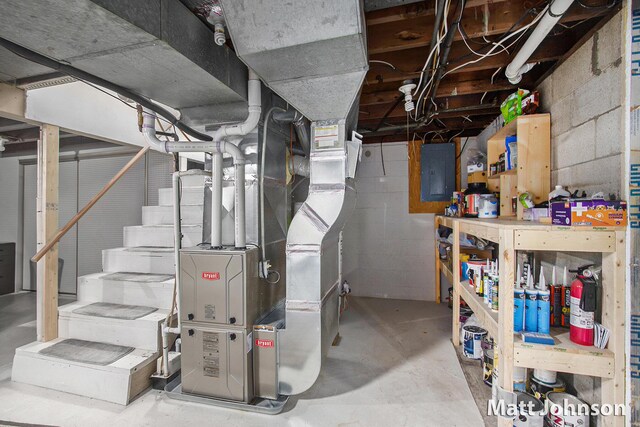 unfinished basement featuring electric panel, stairway, and heating unit