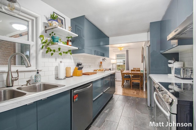 kitchen with under cabinet range hood, stainless steel appliances, blue cabinets, and a sink