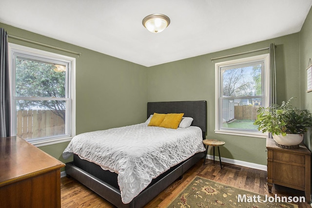 bedroom with wood finished floors, baseboards, and multiple windows