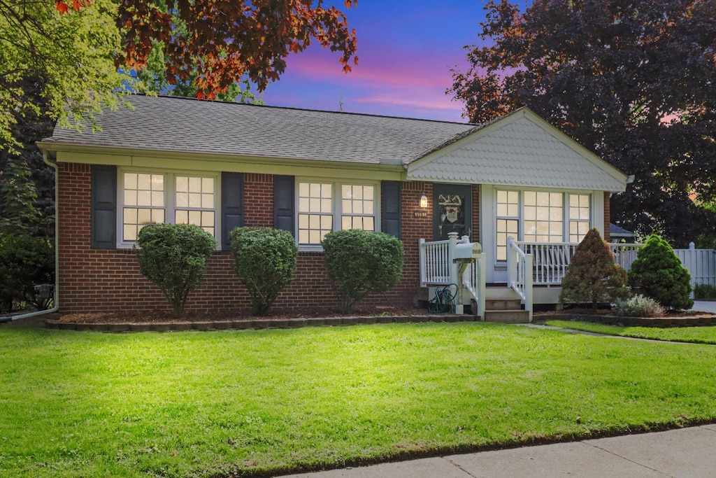 15618 Surrey St, Livonia, MI 48154 - view of front of house with a porch, a lawn, brick siding, and a shingled roof
