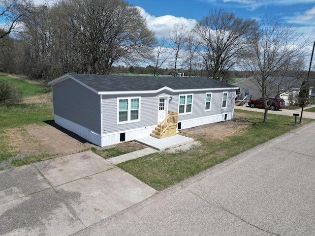 manufactured / mobile home featuring roof with shingles and a front yard