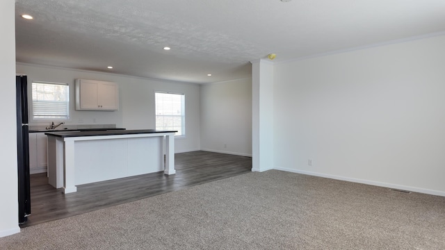 kitchen with dark carpet, dark countertops, crown molding, and a wealth of natural light