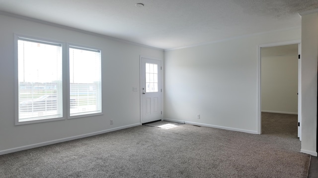 empty room with crown molding, carpet floors, baseboards, and visible vents