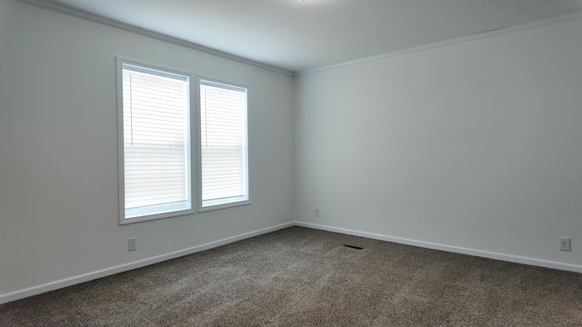 unfurnished room featuring crown molding, baseboards, a healthy amount of sunlight, and dark carpet