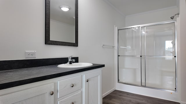 full bath with a stall shower, vanity, crown molding, and wood finished floors