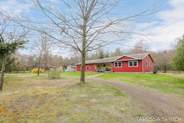 ranch-style home with dirt driveway and a front lawn