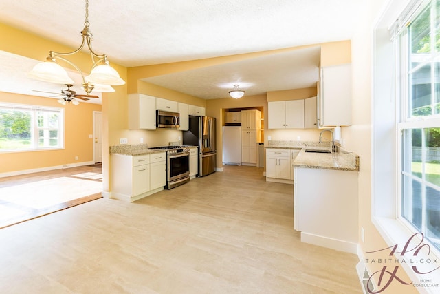 9379 Cook St, Montague, MI 49437 - kitchen featuring appliances with stainless steel finishes, a sink, white cabinetry, baseboards, and light stone countertops