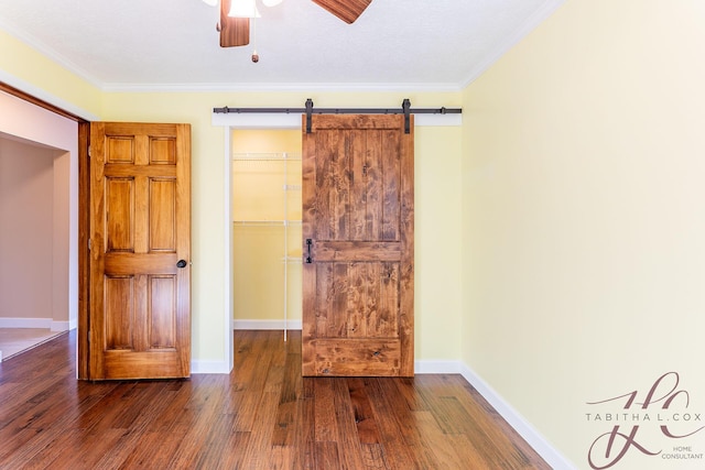 9379 Cook St, Montague, MI 49437 - unfurnished bedroom with wood finished floors, a barn door, crown molding, baseboards, and ceiling fan