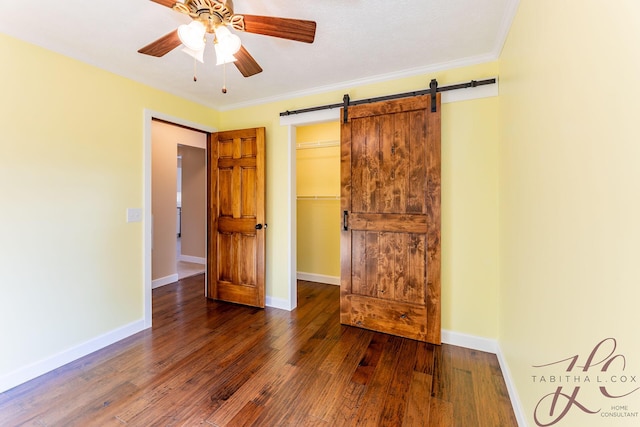 9379 Cook St, Montague, MI 49437 - unfurnished bedroom featuring hardwood / wood-style flooring, a barn door, a walk in closet, baseboards, and crown molding