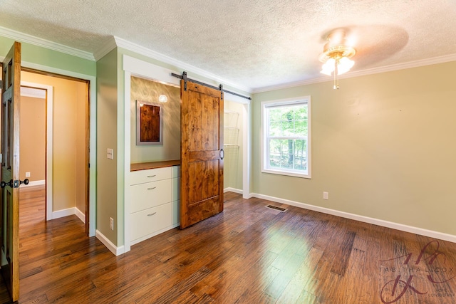 9379 Cook St, Montague, MI 49437 - unfurnished bedroom featuring a barn door, a textured ceiling, dark wood-style floors, baseboards, and crown molding