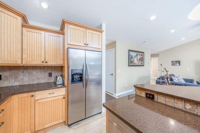 kitchen with light brown cabinets, open floor plan, stainless steel fridge with ice dispenser, decorative backsplash, and recessed lighting