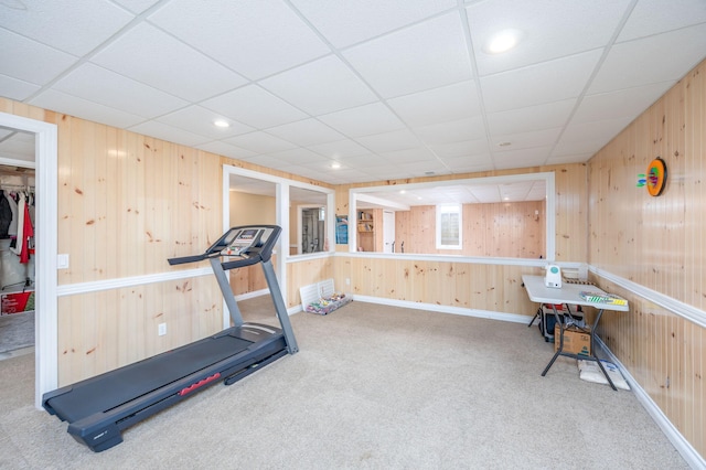 workout room with a drop ceiling, wooden walls, and carpet
