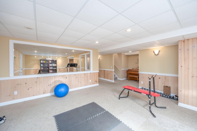 exercise area with baseboards, wooden walls, and carpet flooring
