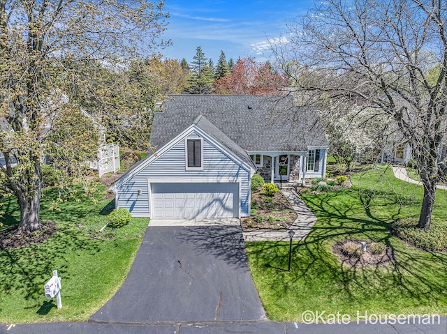view of front of home with a front lawn, a shingled roof, an attached garage, and aphalt driveway