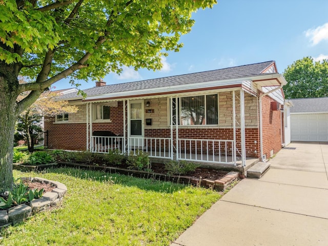 single story home with covered porch, brick siding, a front yard, a chimney, and a detached garage
