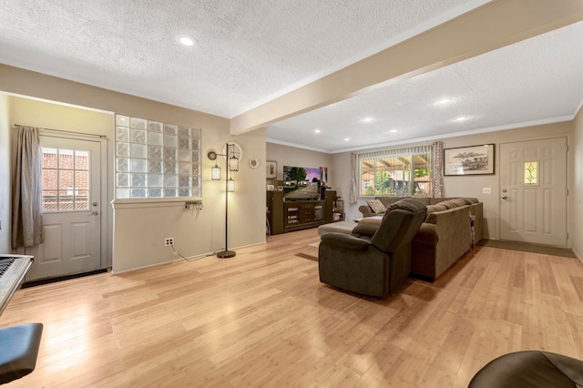 living area featuring a textured ceiling, light wood-style flooring, crown molding, beam ceiling, and recessed lighting