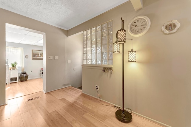 unfurnished room with wood finished floors, baseboards, and a textured ceiling