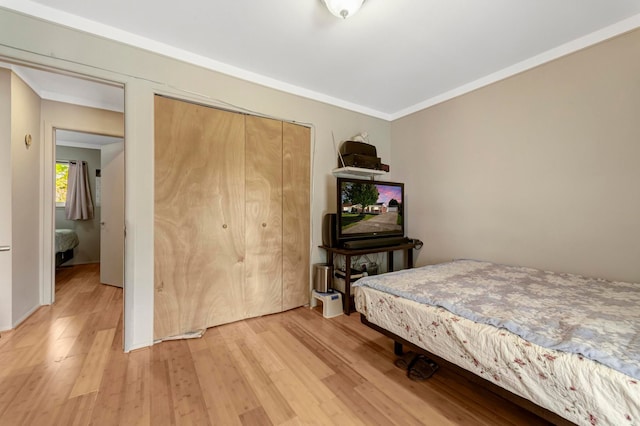 bedroom featuring light wood finished floors, a closet, and ornamental molding