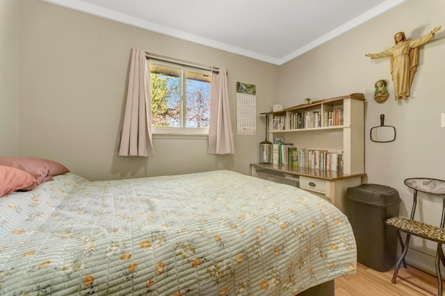 bedroom with ornamental molding and light wood finished floors