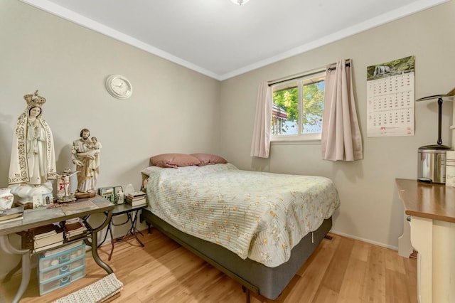 bedroom featuring wood finished floors, ornamental molding, and baseboards