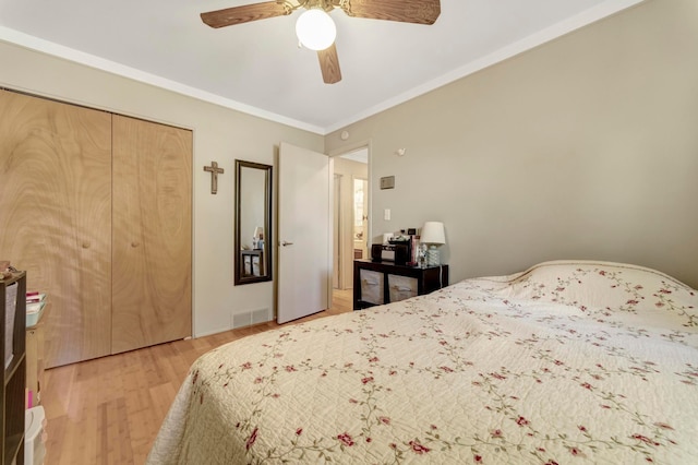 bedroom featuring light wood finished floors, a ceiling fan, a closet, and ornamental molding