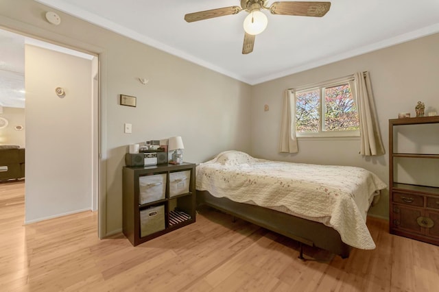 bedroom with light wood-style floors, ornamental molding, ceiling fan, and baseboards