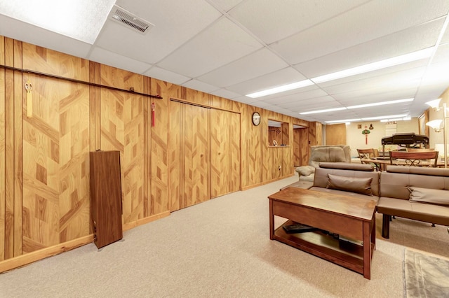 living room featuring carpet floors, wood walls, and a paneled ceiling