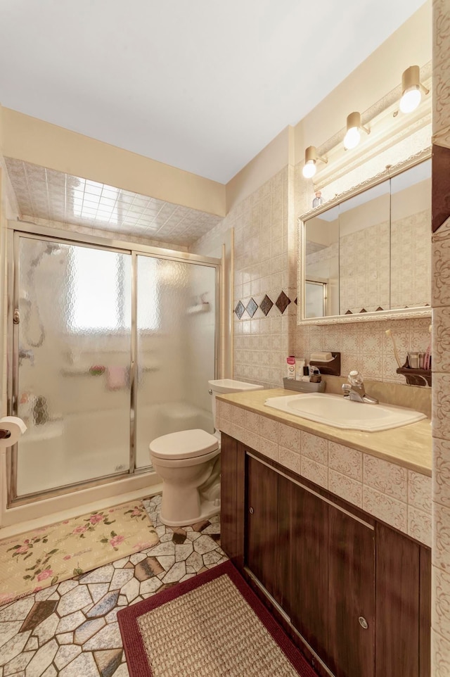 full bath featuring a shower stall, toilet, vanity, and tile walls