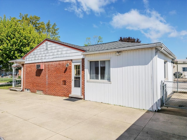 view of front of house with a patio, fence, and roof with shingles