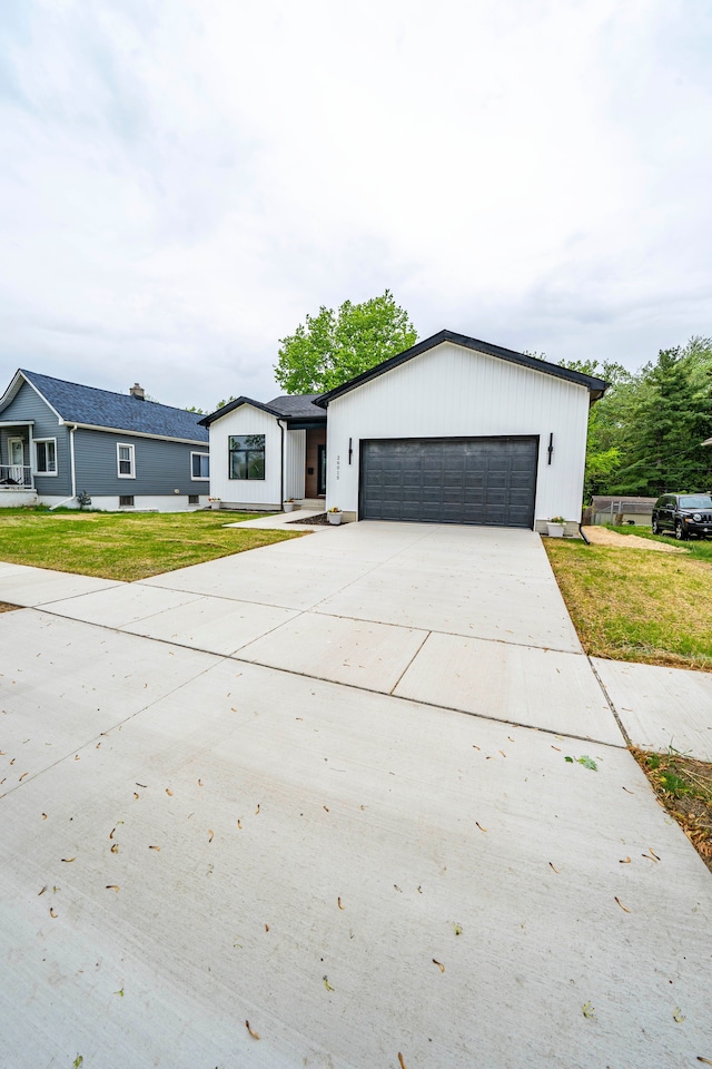 26015 E Huron River Dr, Flat Rock, MI 48134 - view of front of house with an attached garage, concrete driveway, and a front lawn