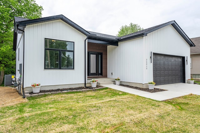 26015 E Huron River Dr, Flat Rock, MI 48134 - view of front of property featuring an attached garage, central air condition unit, driveway, and a front lawn