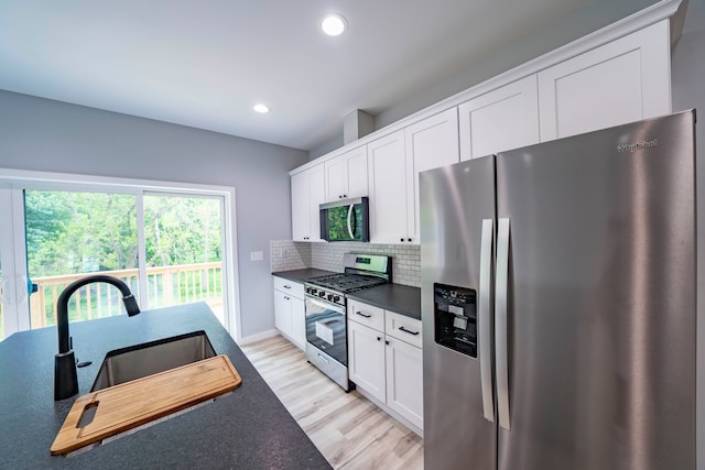 26015 E Huron River Dr, Flat Rock, MI 48134 - kitchen with appliances with stainless steel finishes, dark countertops, tasteful backsplash, light wood-style flooring, and white cabinetry