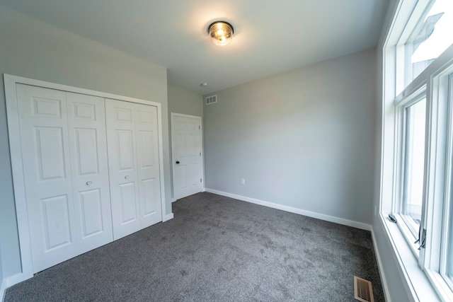 26015 E Huron River Dr, Flat Rock, MI 48134 - unfurnished bedroom with dark colored carpet, baseboards, and a closet