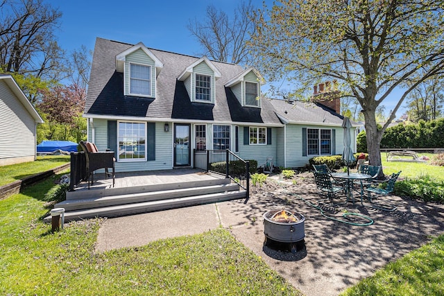 9528 Silverside Dr, South Lyon, MI 48178 - new england style home with a fire pit, a front yard, a deck, a patio, and roof with shingles