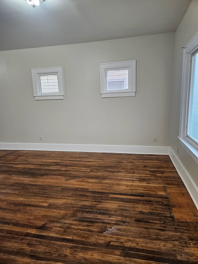 spare room with dark wood-style flooring and baseboards