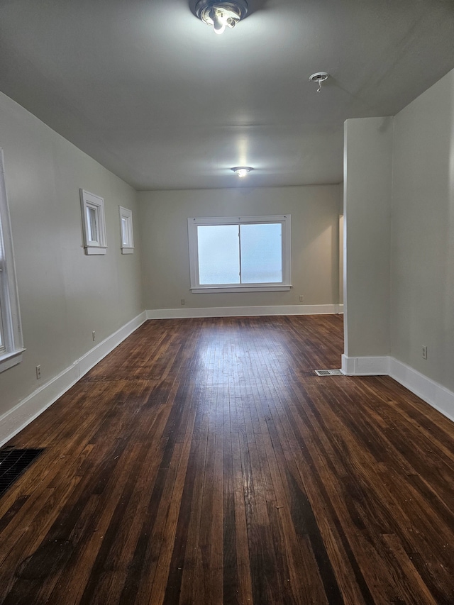 empty room with baseboards and dark wood-type flooring