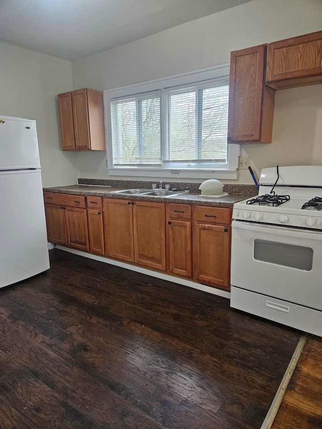 kitchen featuring a sink, white appliances, dark countertops, and brown cabinets