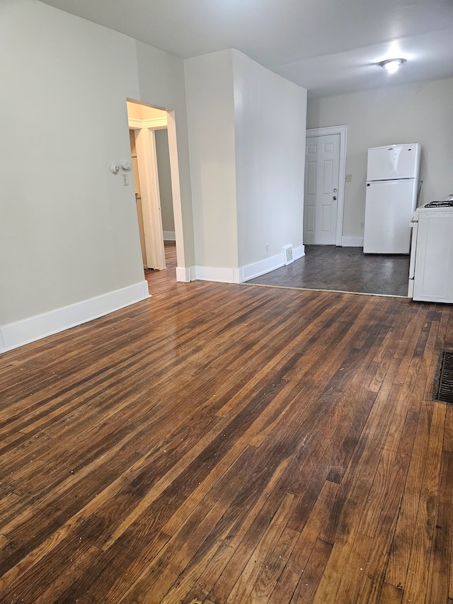 spare room with baseboards, dark wood-style floors, and visible vents
