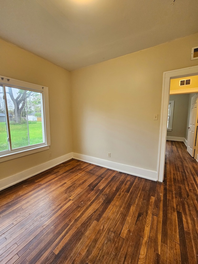 spare room with baseboards, dark wood finished floors, and visible vents
