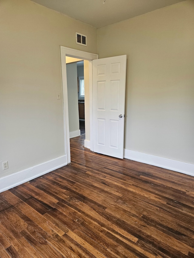 spare room featuring baseboards, visible vents, and dark wood-style floors